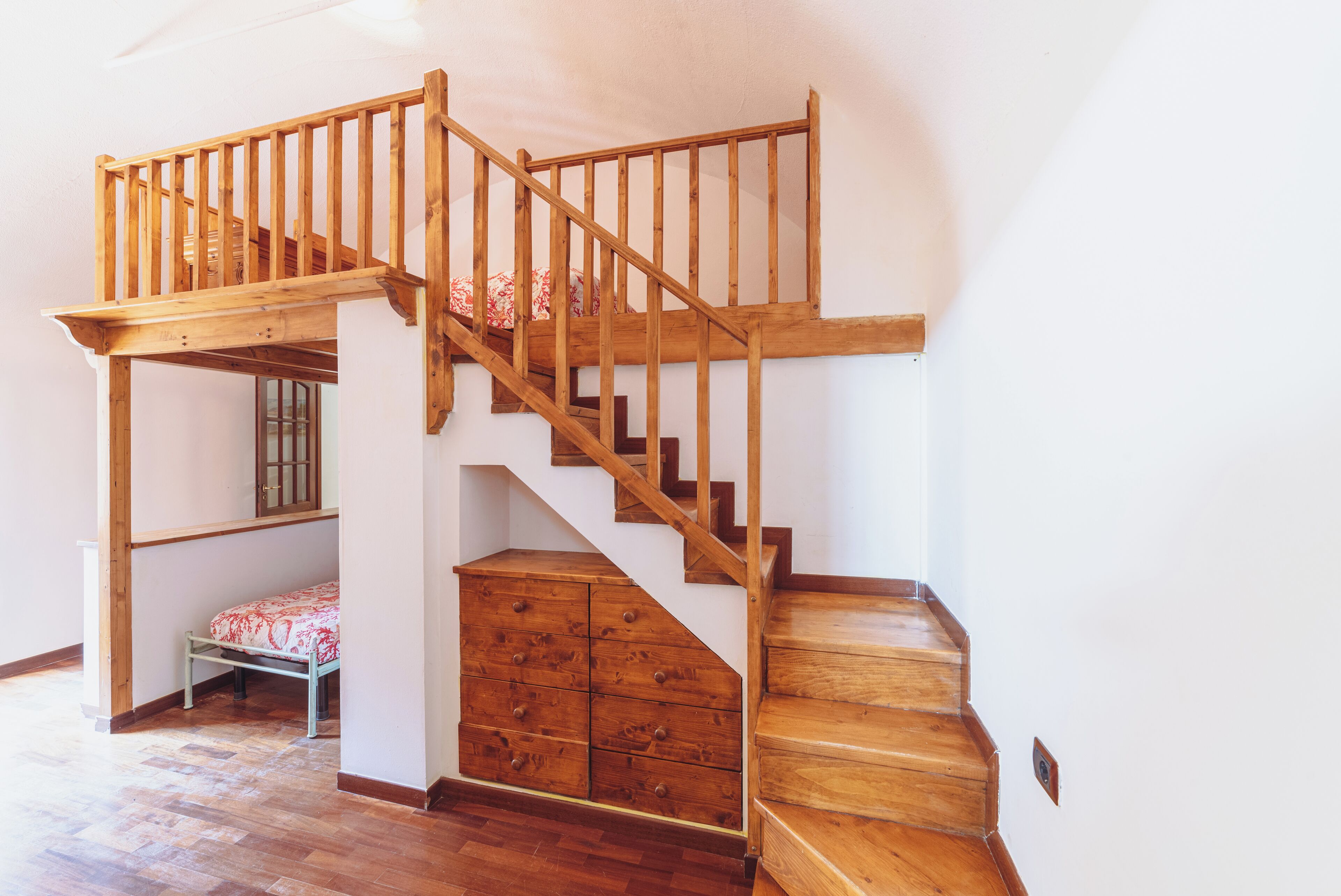 Una escalera de madera con una cama integrada y cajones de almacenamiento.