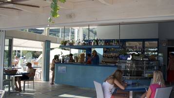 Zona de bar al aire libre con mostrador, asientos y vistas del exterior.