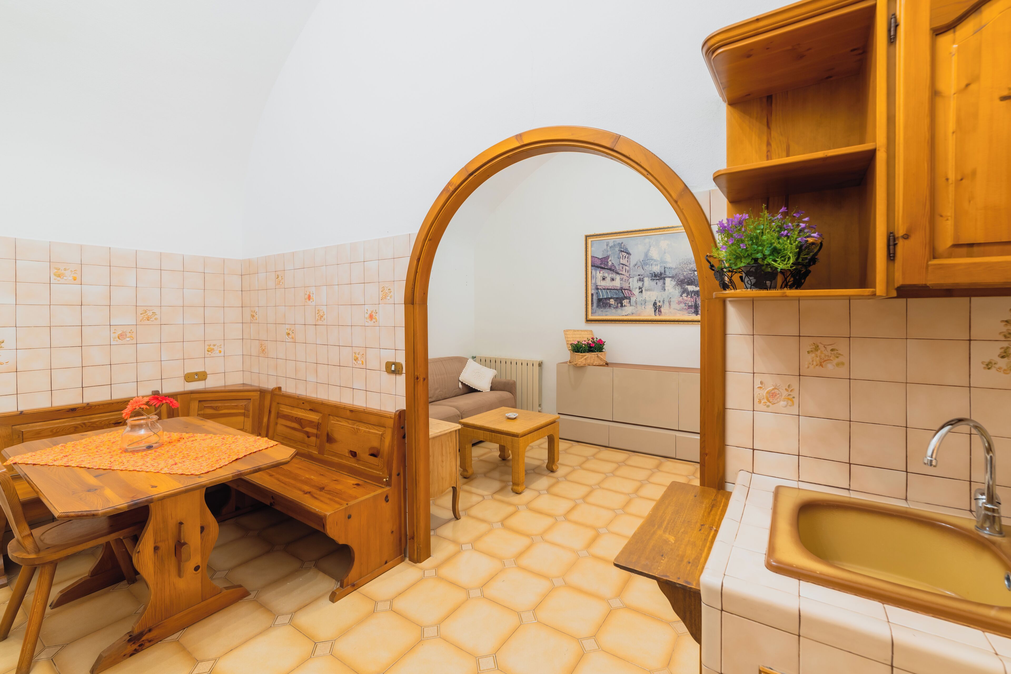 A compact kitchen with a wooden table, bench, and a sink.