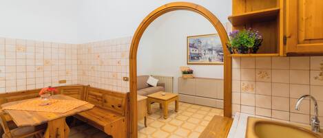 A compact kitchen with a wooden table, bench, and a sink.