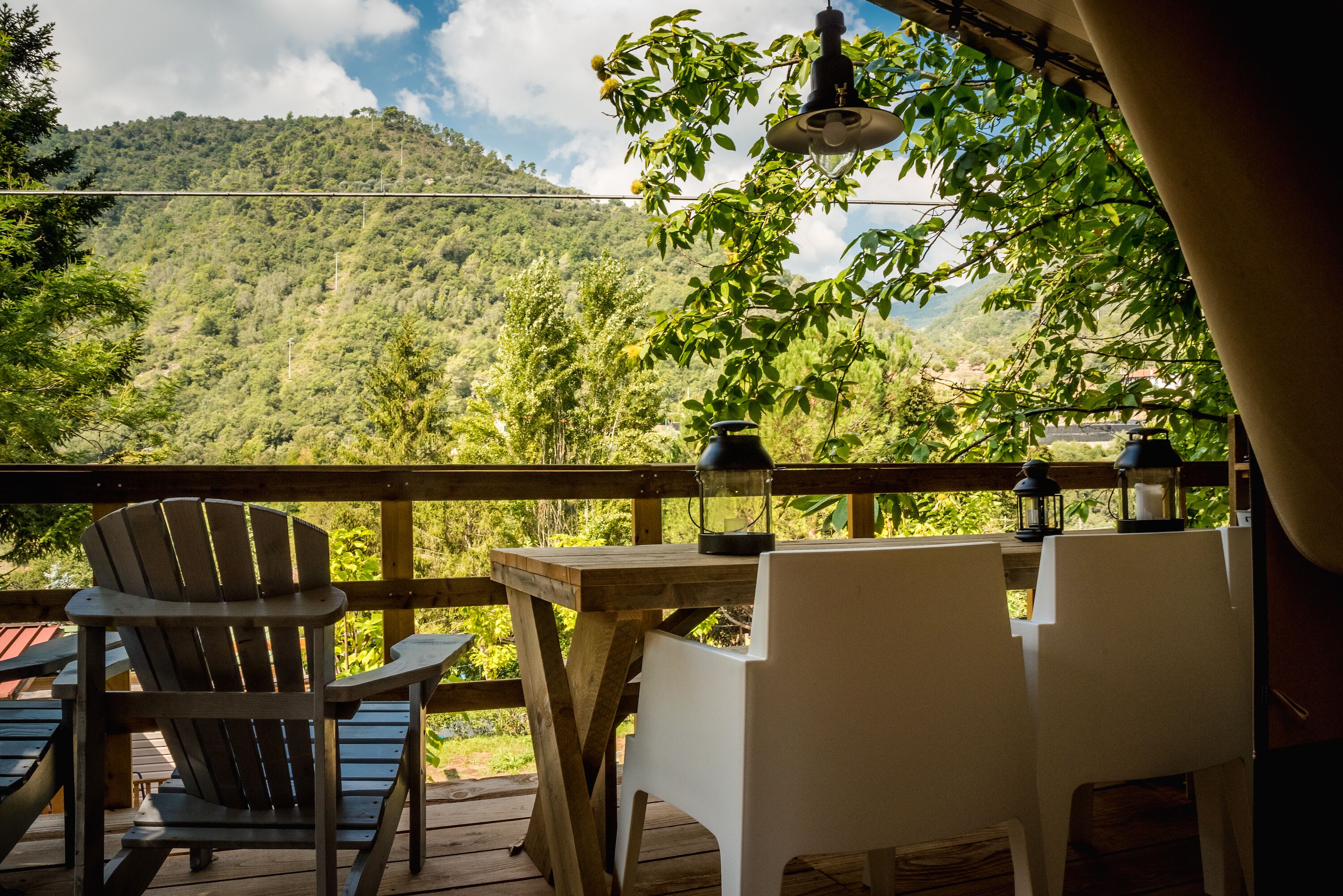 A wooden deck with a table and chairs, overlooking a mountainous landscape.