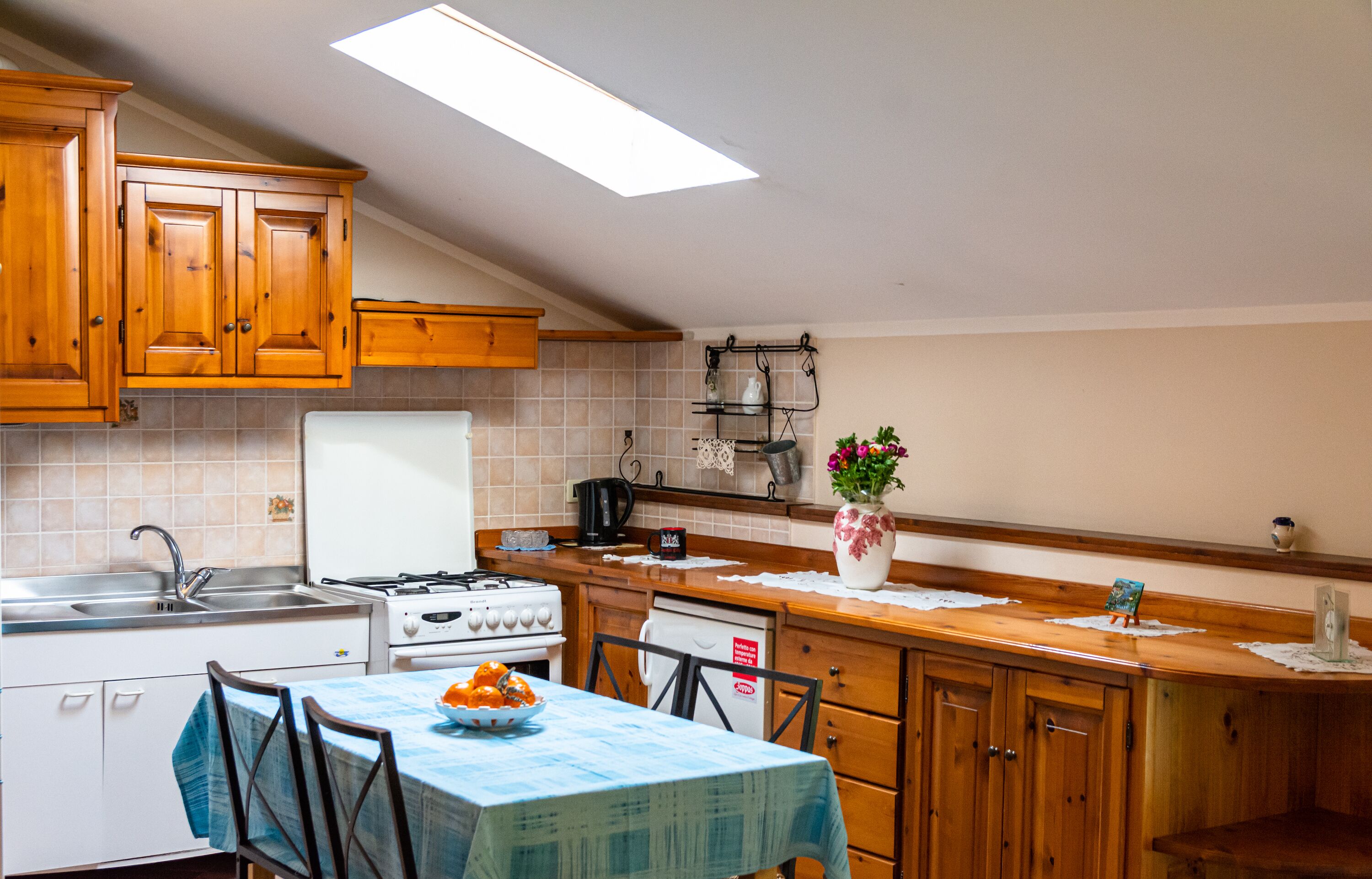 A kitchen with wooden cabinets, a stove, a sink, and a table with chairs.
