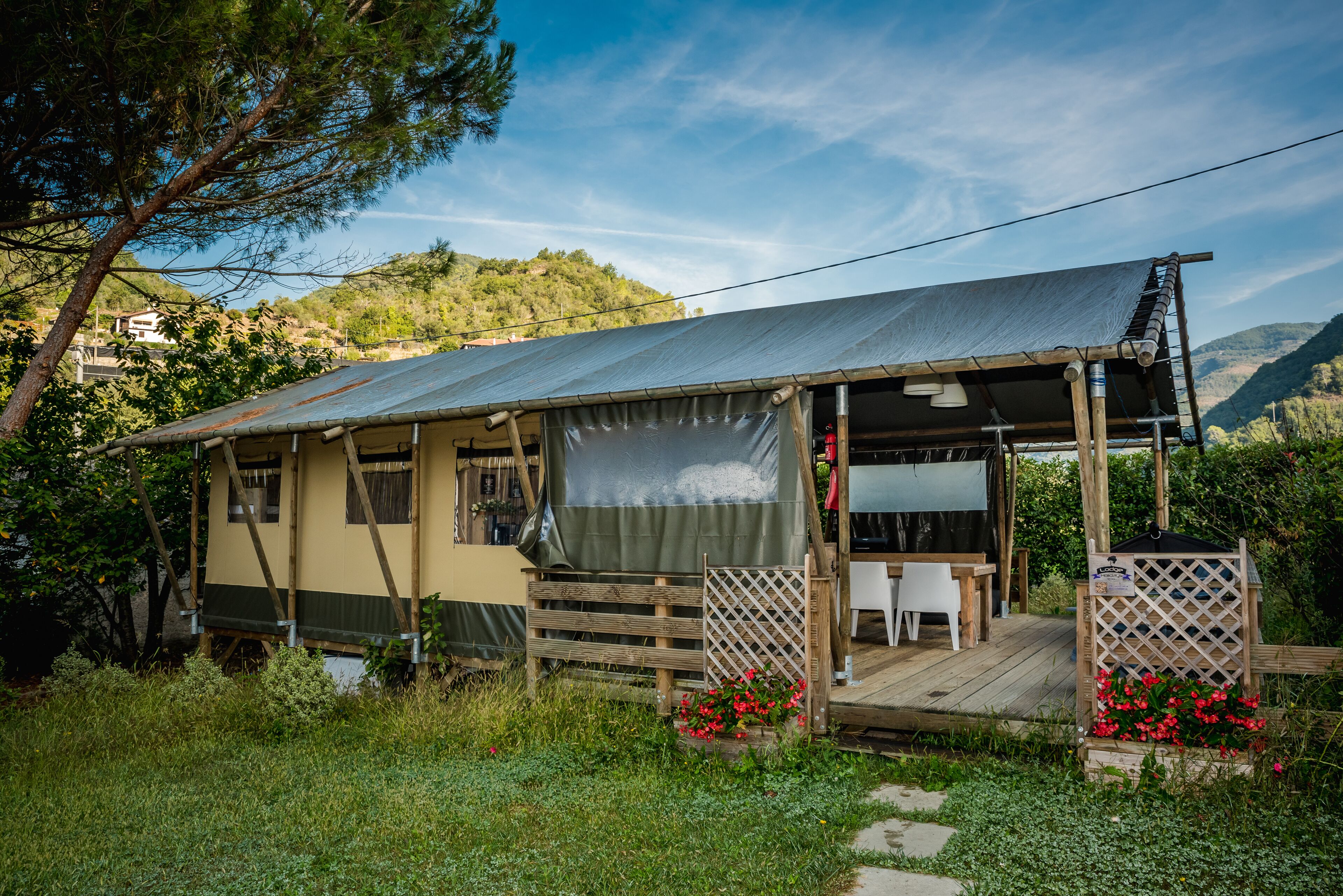 A rustic cabin with a wooden deck, a covered porch, and a view of a mountainous landscape.