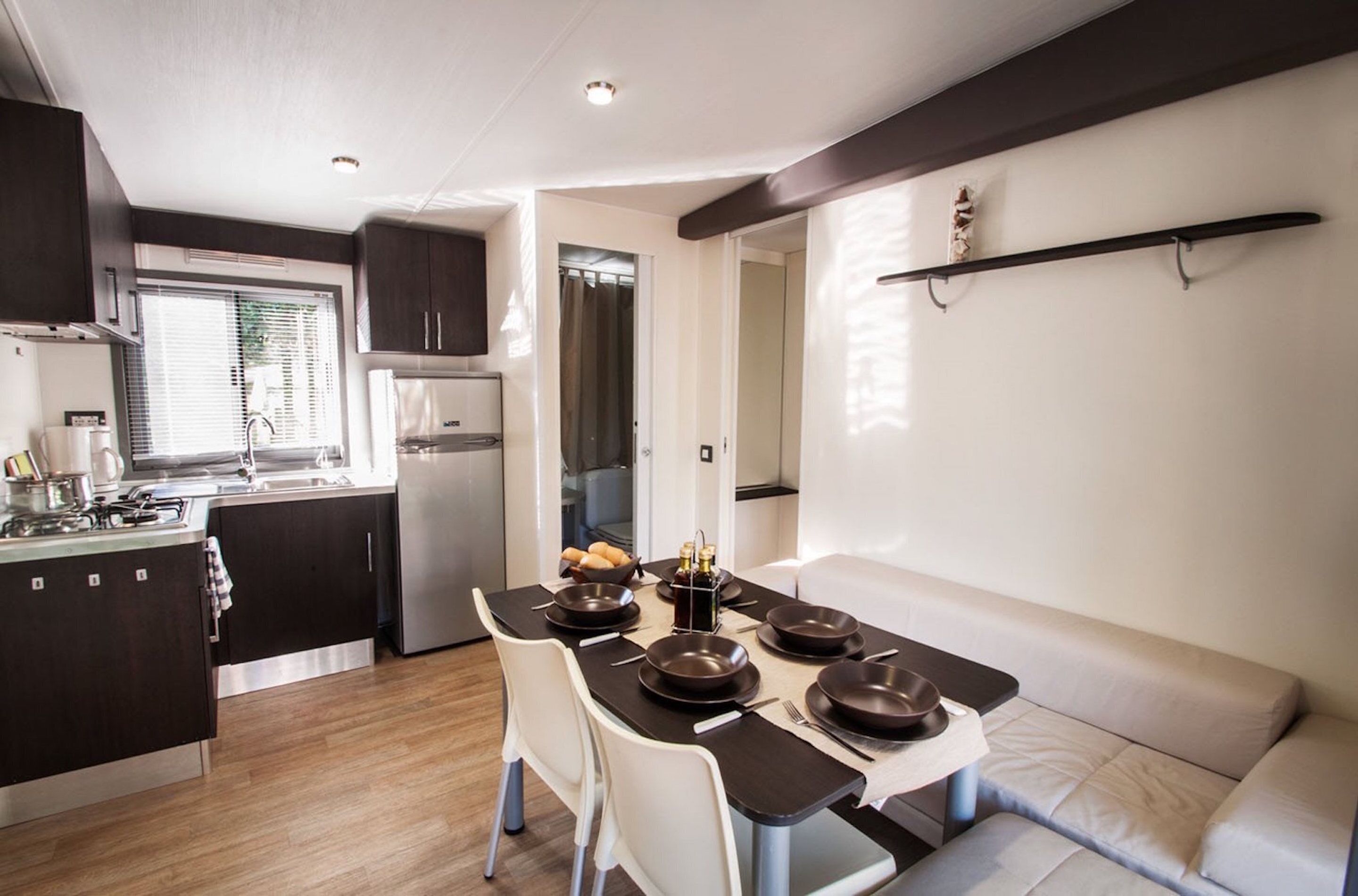 A compact kitchen with modern appliances, a dining area with a table set for four, and a seating area with a sofa.