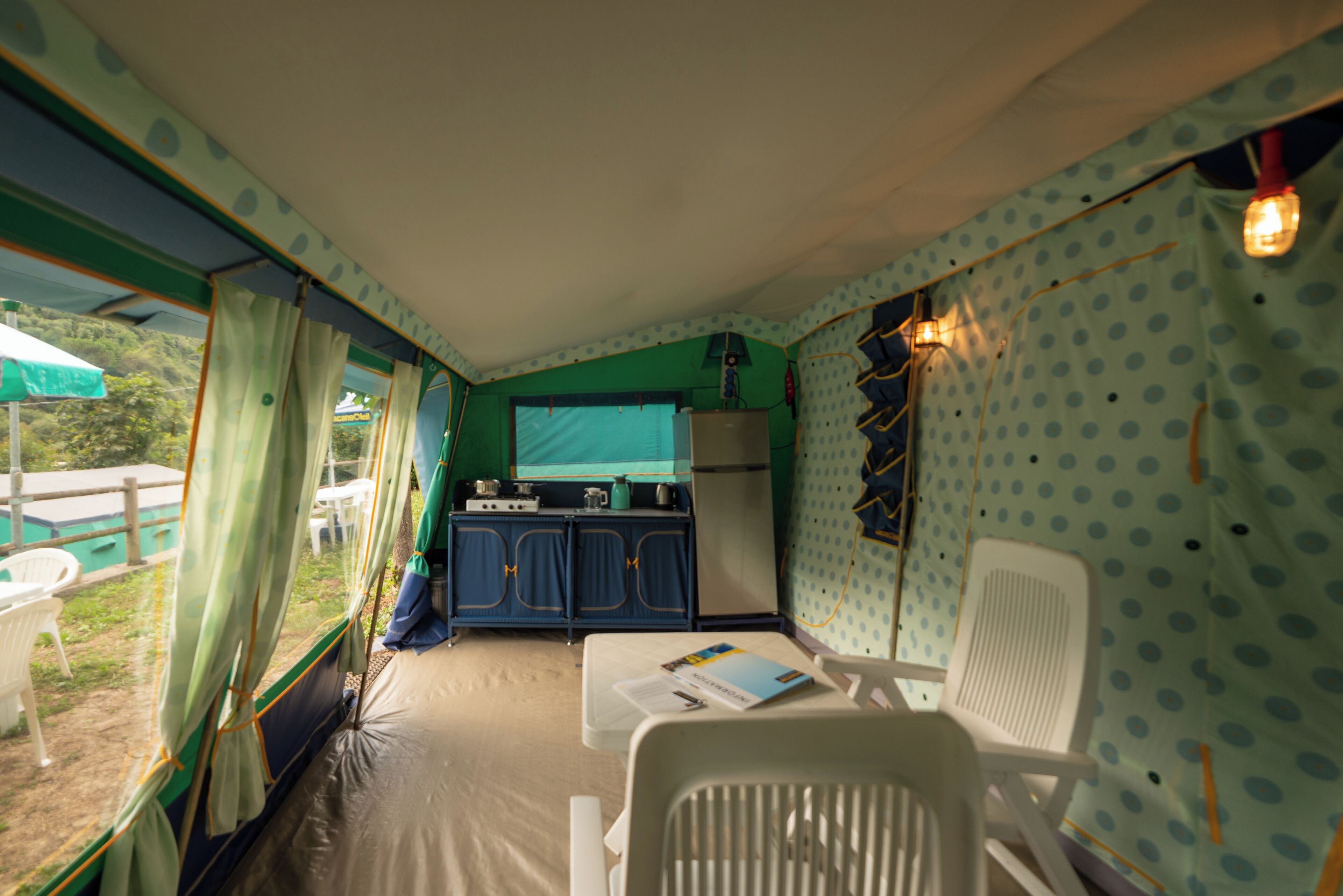 A compact, well-lit room with a kitchenette, a dining area with a table and chairs, and a view of the outdoors through a window.