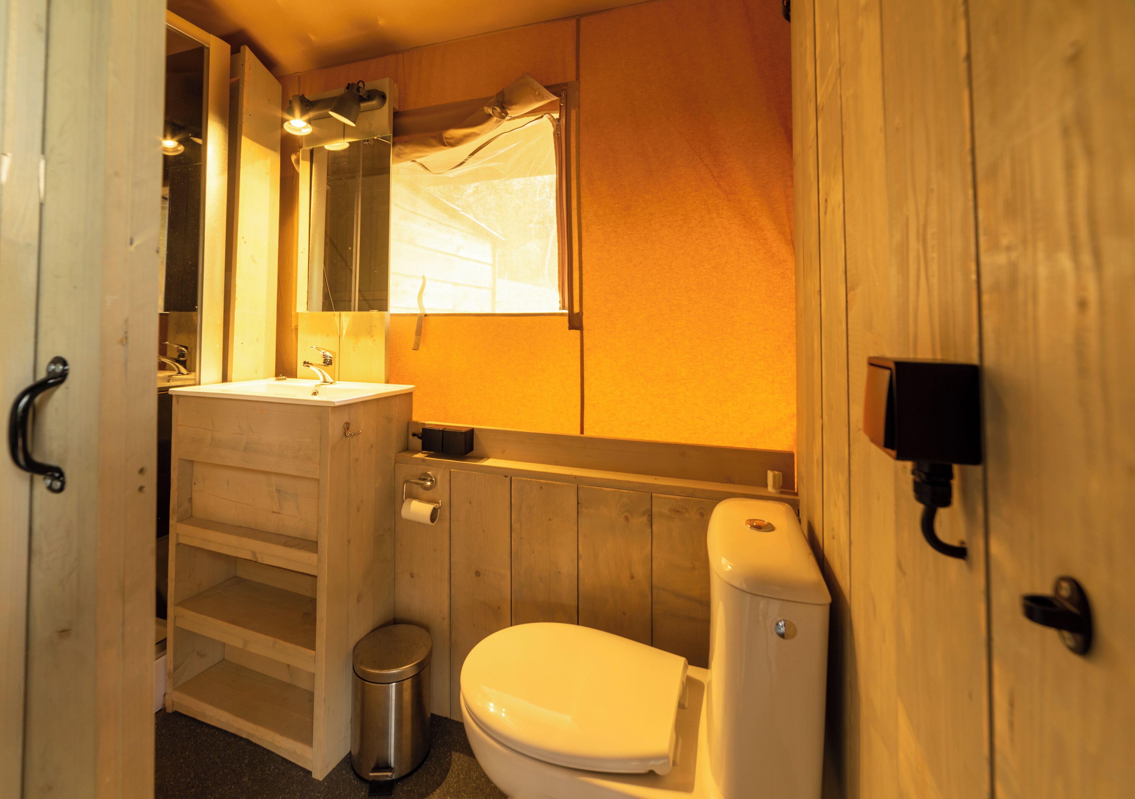 A wooden bathroom with a toilet, sink, and mirror.