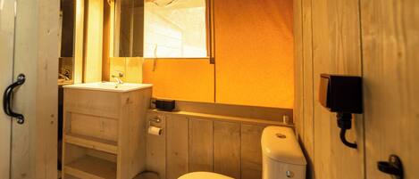 A wooden bathroom with a toilet, sink, and mirror.