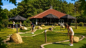Pienoisgolfkenttä, jossa on katettu huvimaja, suuria kiviä ja hyvin hoidettu nurmikko.