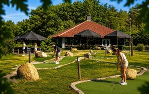 Ein Minigolfplatz mit einem Pavillon, großen Felsen und einem gepflegten Rasen.