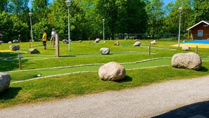 Golfkenttä, jossa on vihreät väylät, hiekkabunkerit ja suuret kivet.