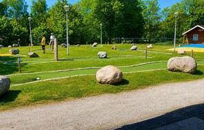 Ein Golfplatz mit grünen Spielbahnen, Sandbunkern und großen Felsen.