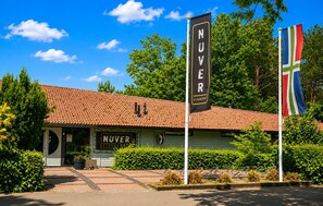 Ein Gebäude mit einem Ziegeldach, einem Schild mit der Aufschrift 'NUVER' und zwei Wimpeln.