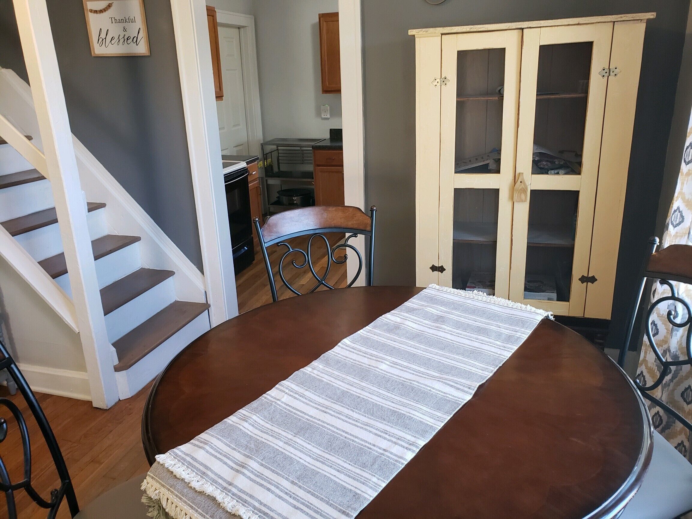 A dining area with a round table, chairs, and a striped table runner.