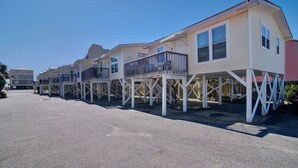A row of beach houses with elevated decks and multiple windows. - Super Nice Quiet Beach Cottage, Pvt Parking, WiFi, Cozy, Spotless, Comfortable.  (Gulf Shores)