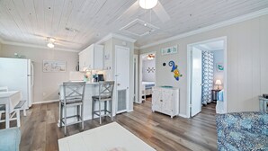A spacious living area with a kitchen, dining area, and a bedroom with a bed and nightstand. - Super Nice Quiet Beach Cottage, Pvt Parking, WiFi, Cozy, Spotless, Comfortable.  (Gulf Shores)