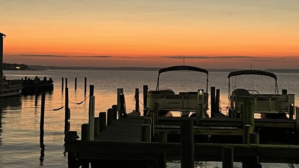 A pier with boats docked, extending into calm water during sunset. - 1st Floor Bayfront 1 bedroom Updated Condo with pool overlooking the bay!! (Ocean City)