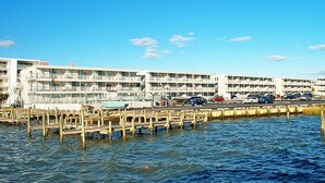 A waterfront hotel with multiple balconies, a parking lot, and a dock area. - 1st Floor Bayfront 1 bedroom Updated Condo with pool overlooking the bay!! (Ocean City)
