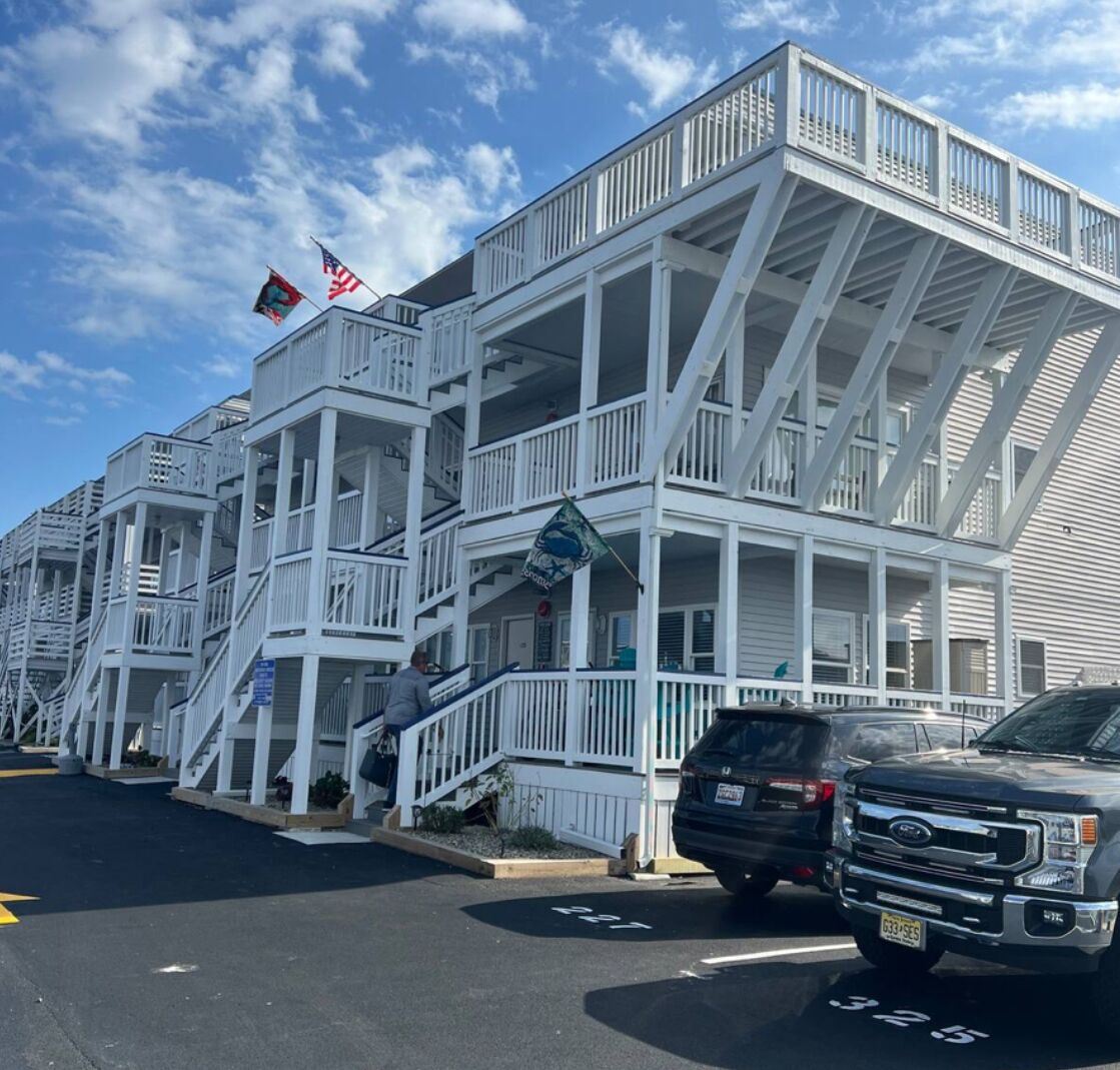 Un hotel de varios pisos con fachada blanca, múltiples balcones y banderas.