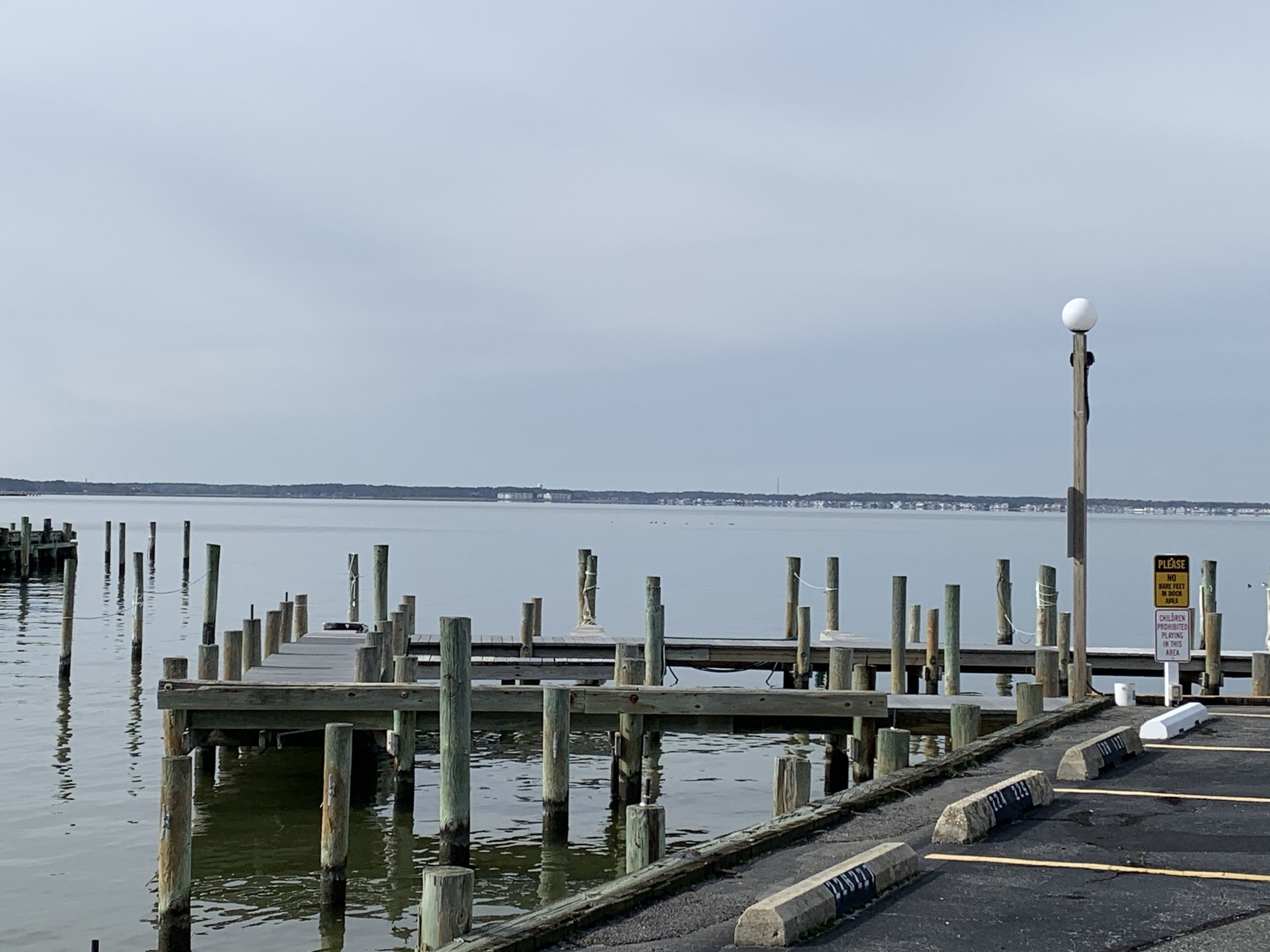 Une jetée en bois s’étendant sur une étendue d’eau calme, sous un ciel dégagé.