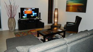Un salon moderne avec un téléviseur à écran plat, un canapé, une table basse et un tableau accroché au mur.