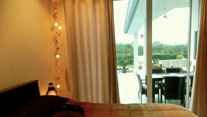 Une chambre à coucher avec un lit, des rideaux et une vue sur un patio extérieur.