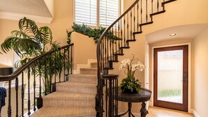 Un escalier recouvert de moquette, avec des balustrades en bois et un pot de fleurs placé à sa base.