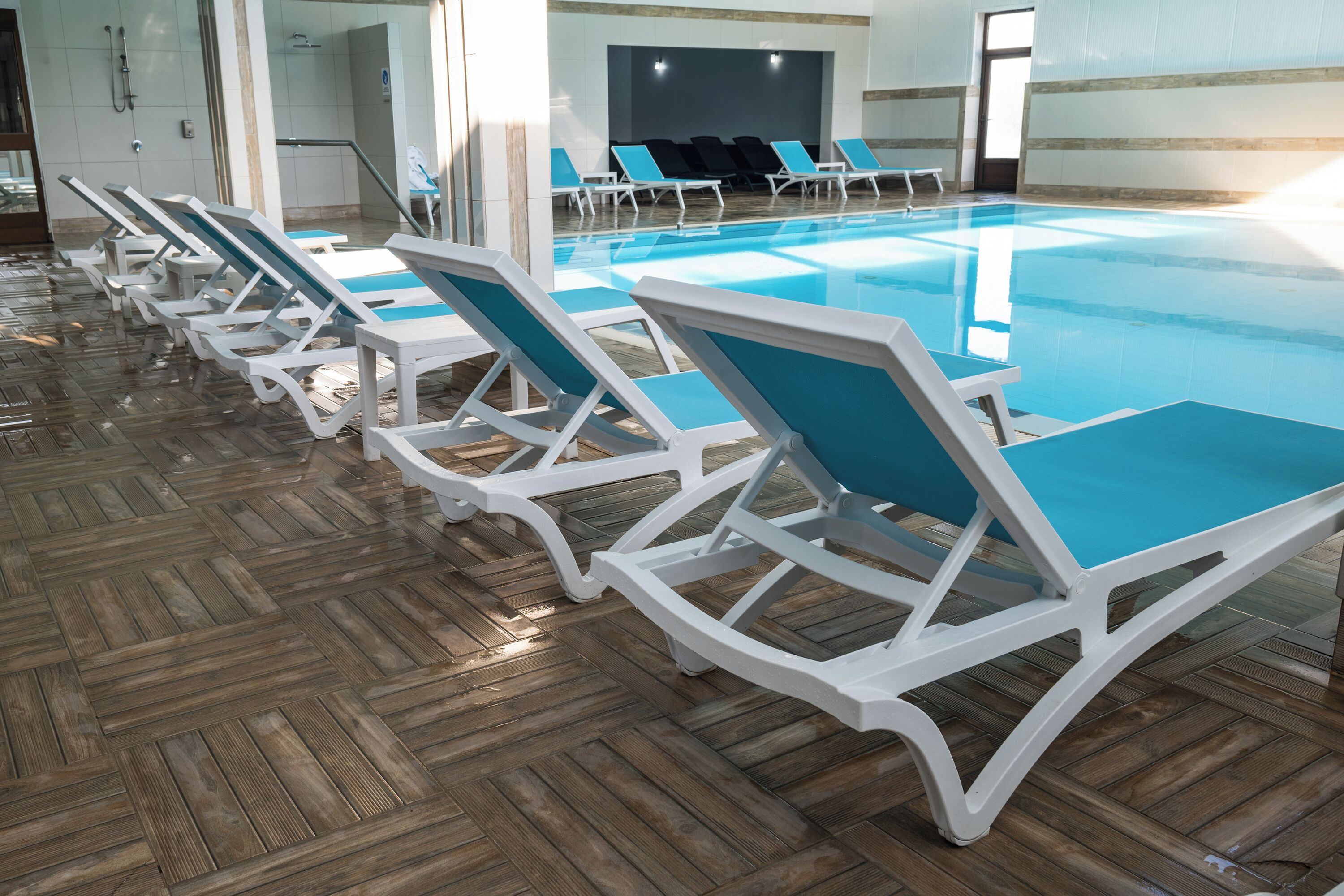 A swimming pool with lounge chairs and a wooden floor.