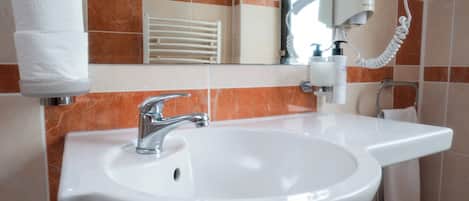 A bathroom with a white sink, a mirror, and a hairdryer on the wall.