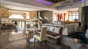 A spacious lobby with a breakfast coffee area, a central seating area with a sofa and chairs, and a staircase leading to upper floors. - Hotel Sole Mio (Novi Sad)