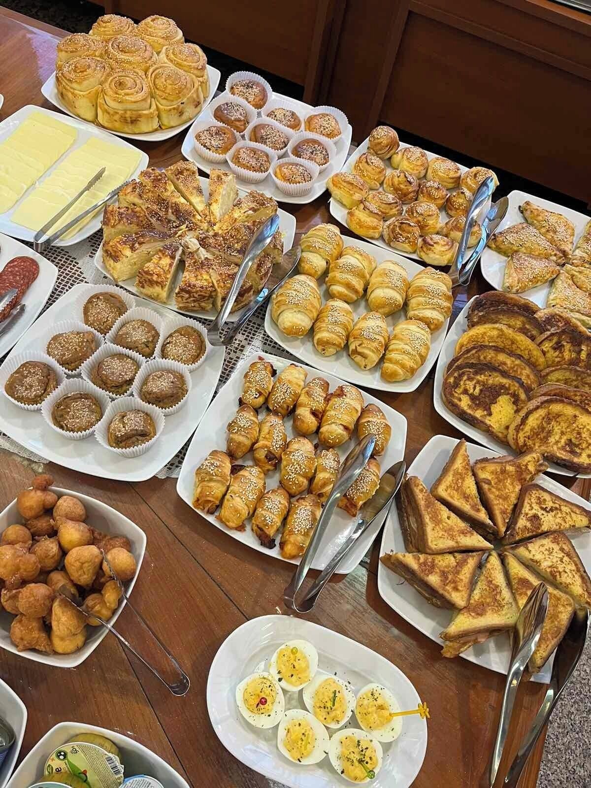 A table filled with various pastries and desserts, including croissants, muffins, and other baked goods.