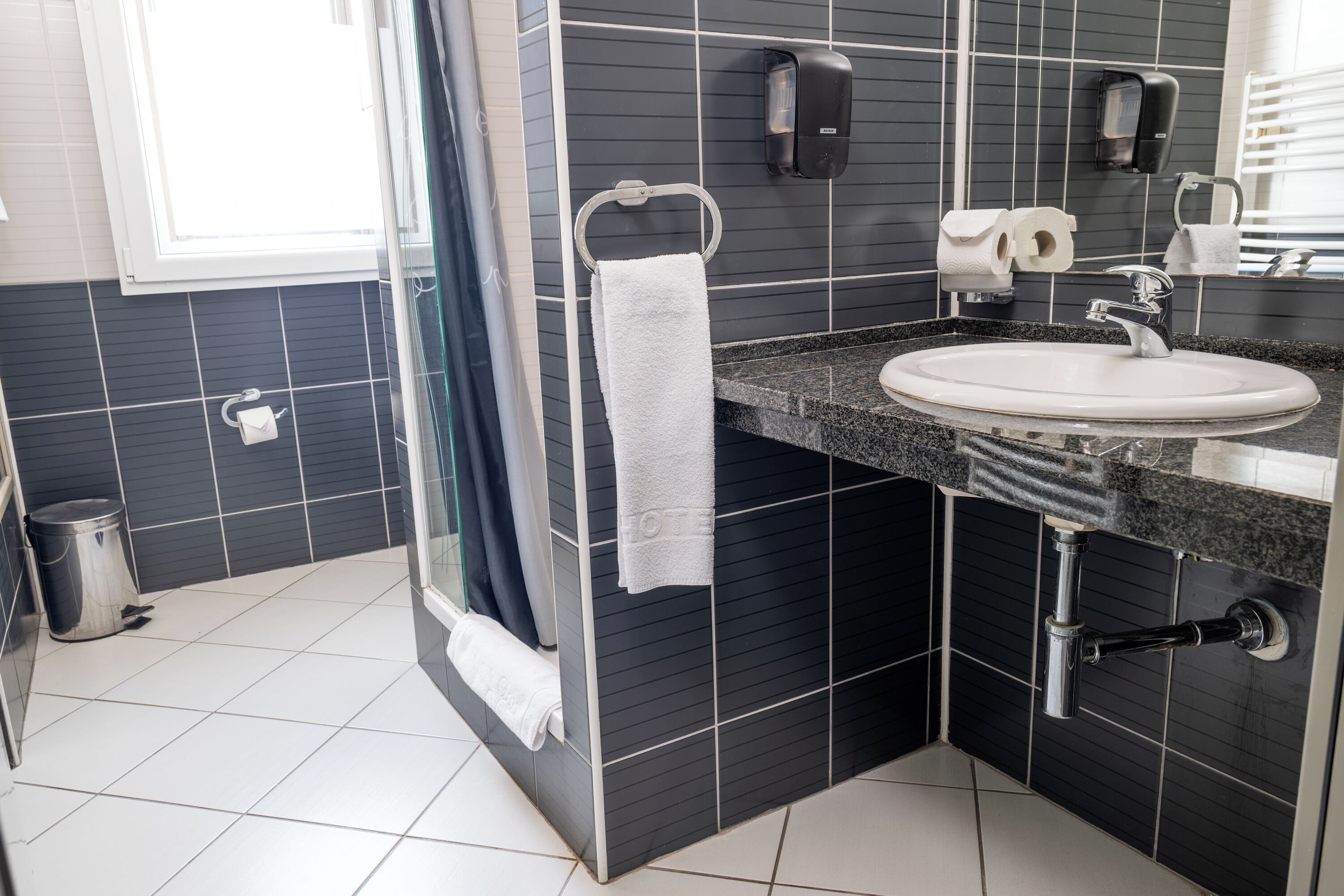 Ein modernes Badezimmer mit Waschbecken, Handtuchhalter und Lufttrockner.