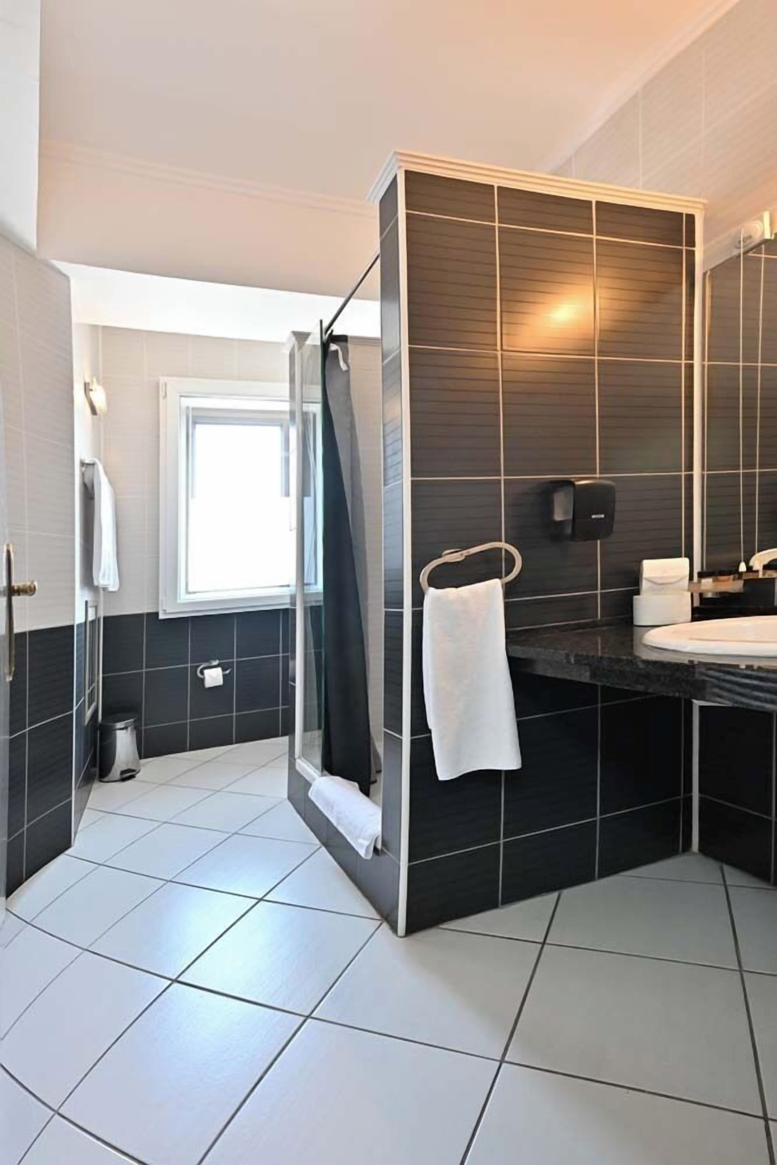 Un baño moderno con ducha, lavamanos e inodoro.