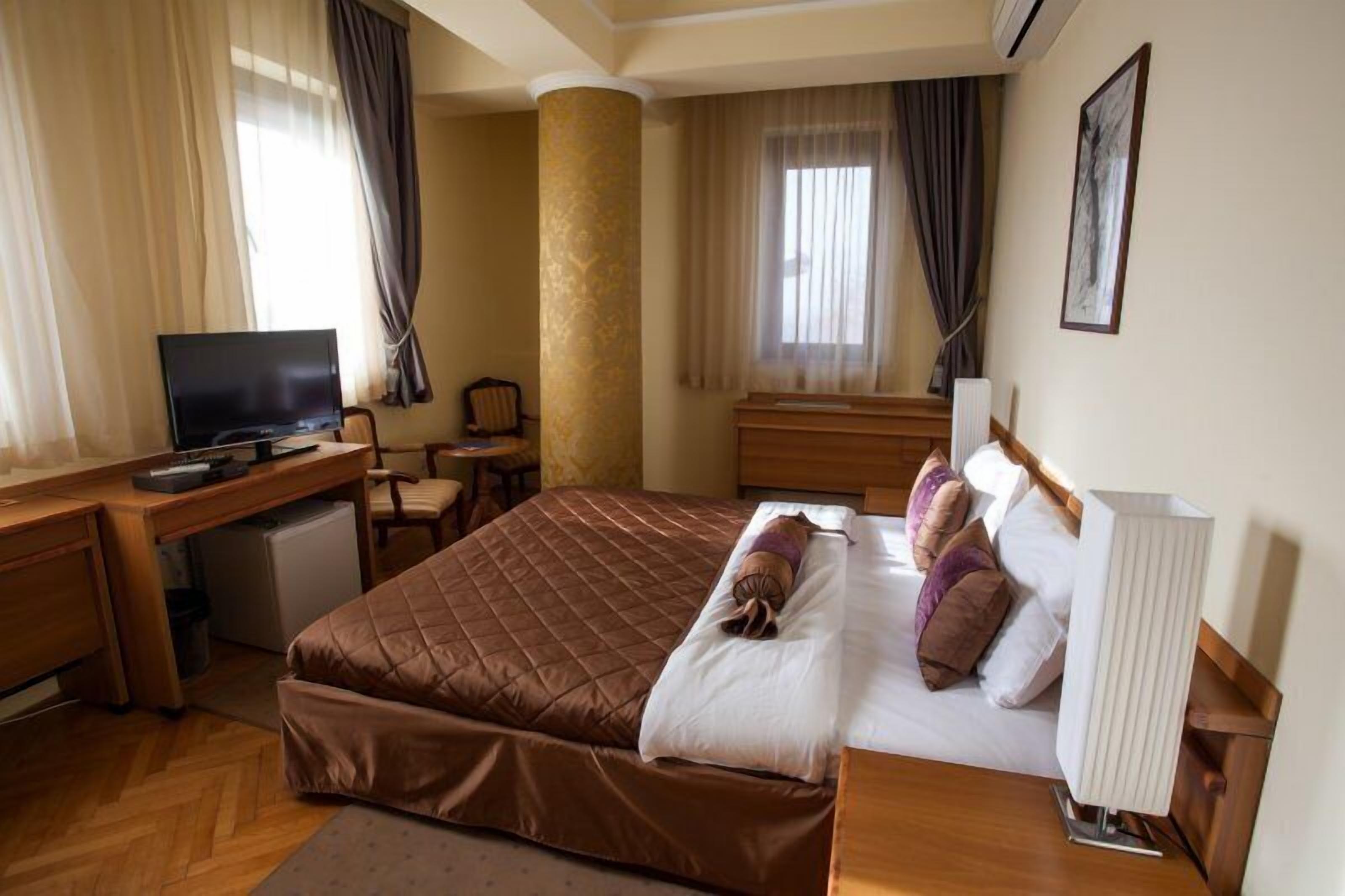 A hotel room with a bed, a desk, a television, and a chair.