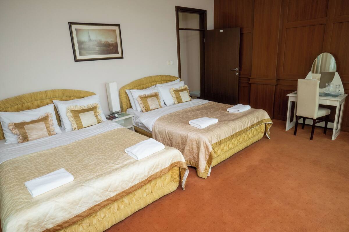 A hotel room with two beds, a desk, and a wardrobe.