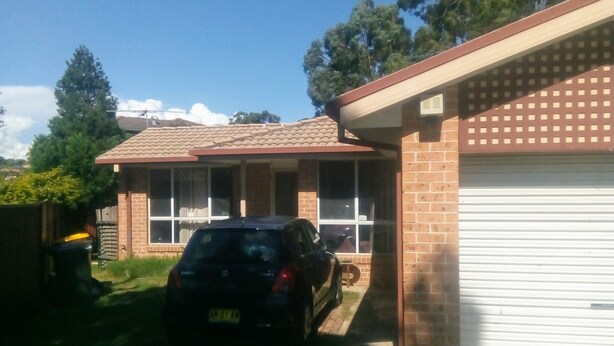 A residential house with a garage, a driveway, and a car parked in the driveway.