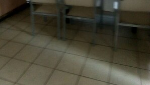 A dining area with a table and chairs, a window with curtains, and a microwave on a counter.
