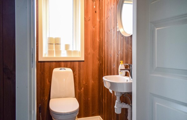Et lille badeværelse med toilet, håndvask og et vindue.