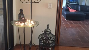 A corner with a table holding candles, a Buddha statue, and a birdcage. - Serendipity Gardens! (Joyner)