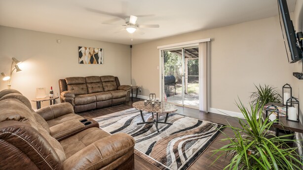 A living room with a brown leather couch, a glass coffee table, and a patterned rug. - Grill, Relax, or Play at Home Away From Home (Shreveport)