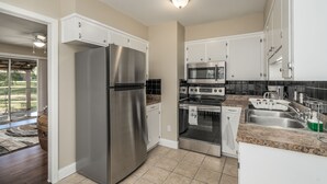 A modern kitchen with stainless steel appliances, white cabinets, and a granite countertop. - Grill, Relax, or Play at Home Away From Home (Shreveport)