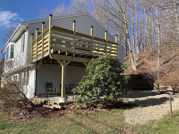 A two-story house with a wooden deck and a covered porch.