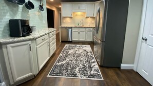A modern kitchen with white cabinets, stainless steel appliances, and a patterned rug. - Newly Renovated AC 4 ACRES 3000sqft home with Full Game Room (Hunter)