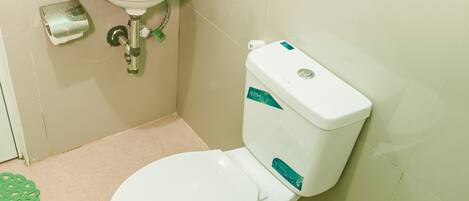 Un baño pequeño con inodoro blanco, lavamanos y dispensador de papel higiénico.