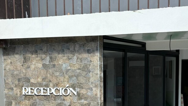 A reception area with a stone wall and a glass door entrance. - Hotel Naralit (Tilaran)