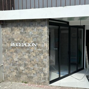 A reception area with a stone wall and a glass door entrance. - Hotel Naralit (Tilaran)
