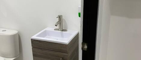 A bathroom with a white sink, a mirror, and a wooden cabinet.