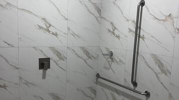 A shower area with a handrail, a showerhead, and a grab bar.