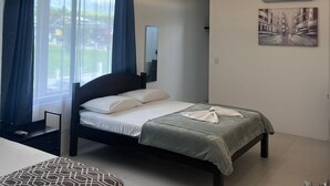 A modern bedroom with a bed, a bedside table, a window with curtains, an air conditioning unit, and a painting on the wall. - Hotel Naralit (Tilaran)
