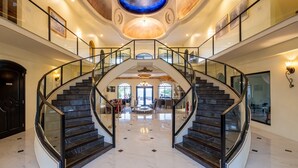 Ein großzügiges, mehrgeschossiges Interieur mit einer zentralen Wendeltreppe, poliertem Marmorboden und einer hohen Decke mit Oberlichter.