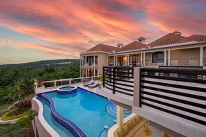 A two-story building with a swimming pool and a view of the surrounding landscape. - An Ultra-Luxurious Resort Style Ocean View Villa. Optional Yacht, Fully Staffed! (Discovery Bay)